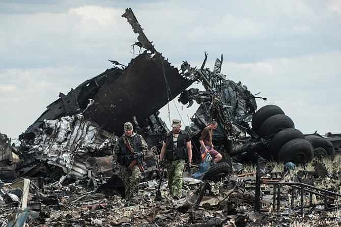Pro-Russian fighters collect ammunition from the site of remnants of a downed Ukrainian army aircraft Il-76 at the airport near Luhansk, Ukraine, Saturday, June 14, 2014. Pro-Russian separatists shot down the military transport plane Saturday in the country's restive east, killing all 49 service personnel on board, Ukrainian officials said. (AP Photo/Evgeniy Maloletka)