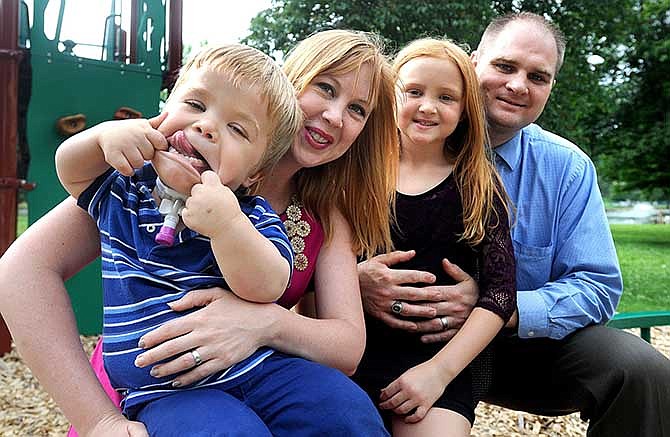 In this June 5, 2014 photo, Izaac Pursley, left, makes a silly face for the camera while having his photo taken with his mother, Sheree, sister, Evee-Kay, and father, Greg, at Capaha Park, in Cape Girardeau, Mo. Six-year-old Izaac was born with a form of dwarfism, and resulting complications have stunted his growth and damaged his lungs. He needed a tracheotomy before he was a year old and uses a ventilator to pump oxygen into his too-small chest when he sleeps at night. (AP Photo, Southeast Missourian, Laura Simon)