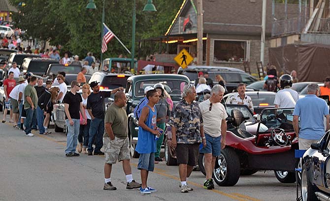 Sightseers and visitors wander between extravagant, old, or customized cars at the Lake Ozark Strip's Hot Summer Nights Festival on Friday, June 13, 2014.
