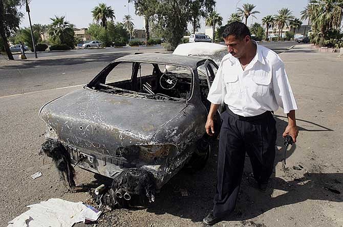 This Sept. 25, 2007 file photo shows an Iraqi traffic policeman inspecting a car destroyed by a Blackwater security detail in al-Nisoor Square in Baghdad, Iraq. In a tale of death and destruction, a federal prosecutor has chronicled for a jury the alleged conduct of four Blackwater security guards accused of killing 14 Iraqis and wounding 18 others in downtown Baghdad nearly seven years ago. In opening statements Tuesday at the trial of the four guards, Assistant U.S. Attorney T. Patrick Martin said the victims were simply trying to get out of the way of gunfire from the Blackwater guards. 