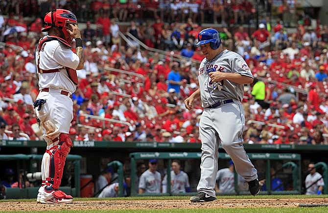 New York Mets' Bartolo Colon, right, scores on a double by Eric Young Jr. as St. Louis Cardinals catcher Yadier Molina, left, watches during the sixth inning of a baseball game Wednesday, June 18, 2014, in St. Louis.