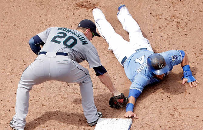 Kansas City Royals' Alex Gordon (4) beats the tag by Seattle Mariners first baseman Logan Morrison (20) during a pickoff-attempt at first base during the seventh inning of a baseball game on Saturday, June 21, 2014, in Kansas City, Mo. 