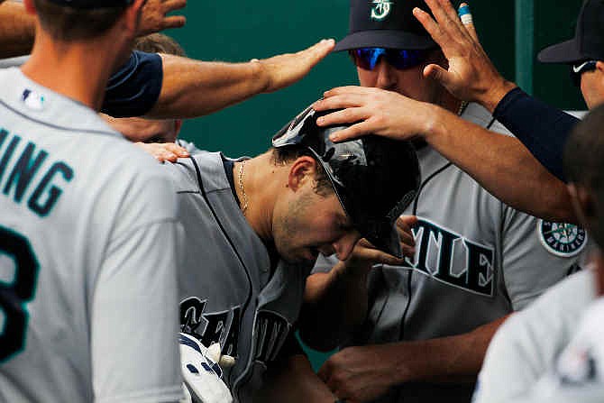 Seattle Mariners' Mike Zunino, center, is congratulated by his teammates in the dugout after hitting a home run against the Kansas City Royals in the seventh inning of a baseball game at Kauffman Stadium in Kansas City, Mo., Sunday, June 22, 2014.