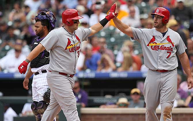 St. Louis Cardinals' Matt Adams, front left, is congratulated after hitting a two-run home run by Matt Holliday, front right, as Colorado Rockies catcher Wilin Rosario looks away in the fifth inning of a baseball game in Denver on Wednesday, June 25, 2014.