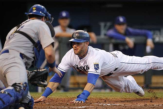 Kansas City Royals' Alex Gordon dives into home plate to score as Los Angeles Dodgers catcher A.J. Ellis is unable to make the tag in the fourth inning of a baseball game at Kauffman Stadium in Kansas City, Mo., Wednesday, June 25, 2014.