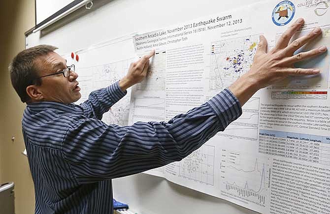 Austin Holland, research seismologist at the Oklahoma Geological Survey, hangs up a chart depicting earthquake activity at their offices at the University of Oklahoma in Norman, Okla., Thursday, June 26, 2014. Earthquakes that have shaken Oklahoma communities in recent months have damaged homes, alarmed residents and prompted lawmakers and regulators to investigate what's behind the temblors - and what can be done to stop them. 