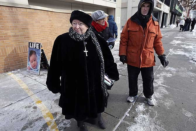 This Dec. 17, 2013 file photo shows anti-abortion protester Eleanor McCullen, of Boston, left, standing at the painted edge of a buffer zone as she protests outside a Planned Parenthood location in Boston. In a unanimous ruling Thursday, June 26, 2014, the Supreme Court struck down a 35-foot protest-free zone outside abortion clinics in Massachusetts, saying that extending a buffer zone 35 feet from clinic entrances violates the First Amendment rights of protesters.