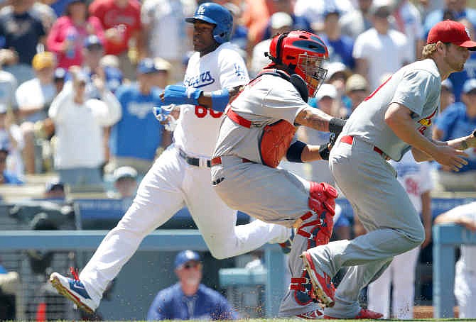 Los Angeles Dodgers' Yasiel Puig, left, scores behind St. Louis Cardinals catcher Yadier Molina, center, and starting pitcher Shelby Miller, right, taking a throw from the outfield on a single by Dodgers' Matt Kemp in the fourth inning of a baseball game on Sunday, June 29, 2014, in Los Angeles.