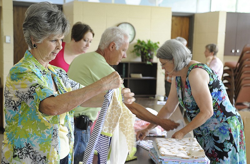 Nancy Epple folds a piece of baby clothing to be included in one of the 55-60 "layette" kits that were assembled at Community Christian Church on Sunday. Most of the kits will be given to Church World Service, an international organization that distributes the kits to new parents.