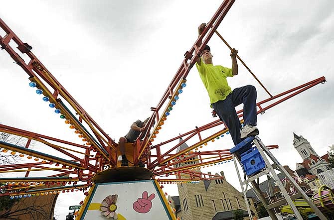 Southern Fun Carnival's Mikeal Fuller, right, and Jerry Hansen work to install the "Far Out" swing near the intersection of East Capitol Avenue and Monroe Street on Tuesday as carnival workers set up the midway in preparation for downtown's upcoming Salute to America festivities which begin Thursday evening.