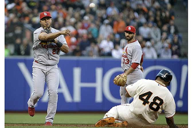 St. Louis Cardinals shortstop Jhonny Peralta, left, turns a double play as San Francisco Giants' Pablo Sandoval, right, is forced out at second base in the second inning of their baseball game Tuesday, July 1, 2014, in San Francisco. The Giants' Michael Morse was out at first base on the play. In the background is Cardinals second baseman Matt Carpenter.