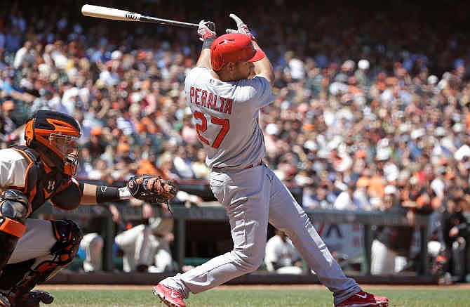 St. Louis Cardinals' Jhonny Peralta (27) singles in the seventh inning of their baseball game against the San Francisco Giants as Giants catcher Buster Posey looks on Thursday, July 3, 2014, in San Francisco. St. Louis won the game 7-2.