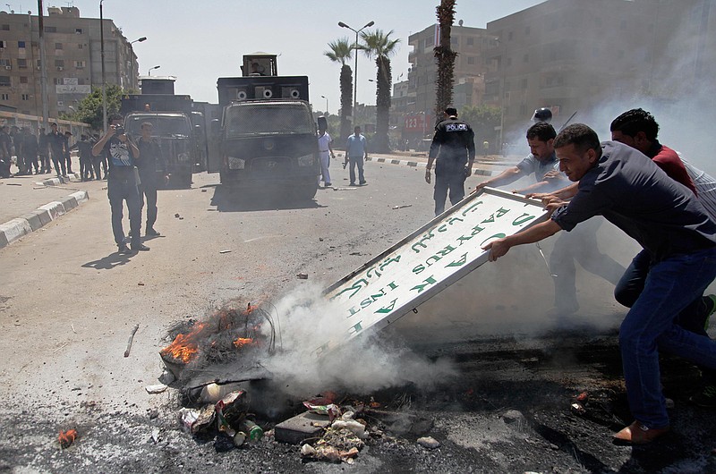 Men try to clear burning debris out of a street after clashes between Egypt's security forces and supporters of ousted President Mohammed Morsi in Cairo's twin city of Giza, Egypt, Friday. A bomb accidentally exploded on a farm Friday southwest of the Egyptian capital, killing at least three suspected militants who were handling it, a security official said.