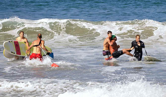 In this photo by Laura Joyce of goofyfootphotography.com, two men carry a swimmer, second from right, after he was bitten by a great white shark, as lifeguards close in at left in the ocean off Southern California's Manhattan Beach, Saturday, July 5, 2014. The man, who was with a group of long-distance swimmers when he swam into a fishing line, was bitten on a side of his rib cage according to Rick Flores, a Los Angeles County Fire Department spokesman. The man's injuries were not life-threatening and he was taken to a hospital conscious and breathing on his own, Flores said. 