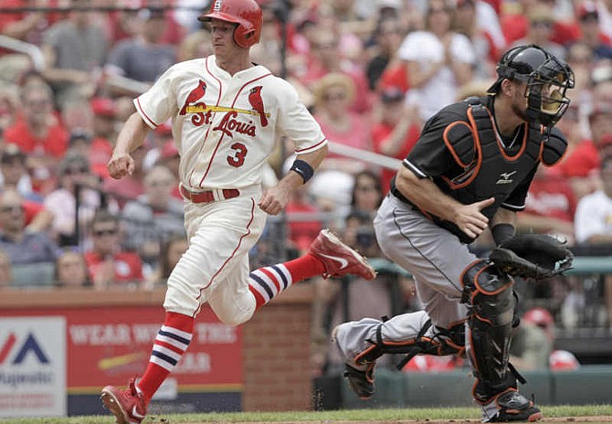 St. Louis Cardinals' Mark Ellis (3) scores from second on a single by Matt Holliday as Miami Marlins catcher Jeff Mathis waits for a late throw in the fourth inning of a baseball game, Saturday, July 5, 2014 in St. Louis.