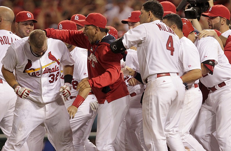 Matt Adams is congratulated by his Cardinal teammates after hitting a two-run walk-off home run in the ninth inning of Monday night's game against the Pirates at Busch Stadium.