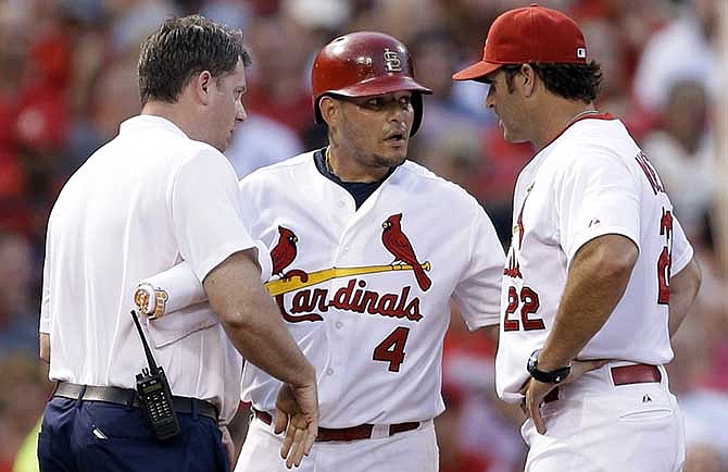 St. Louis Cardinals' Yadier Molina, center, is checked on by manager Mike Matheny, right, and trainer Chris Conroy after injuring his hand while sliding into third during the second inning of a baseball game against the Pittsburgh Pirates Wednesday, July 9, 2014, in St. Louis.