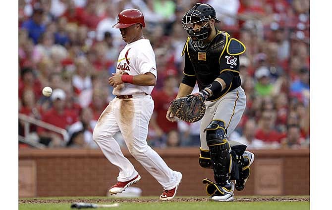 St. Louis Cardinals' Kolten Wong, left, scores on a sacrifice fly by Matt Carpenter as the throw gets away from Pittsburgh Pirates catcher Russell Martin during the third inning of a baseball game Thursday, July 10, 2014, in St. Louis.