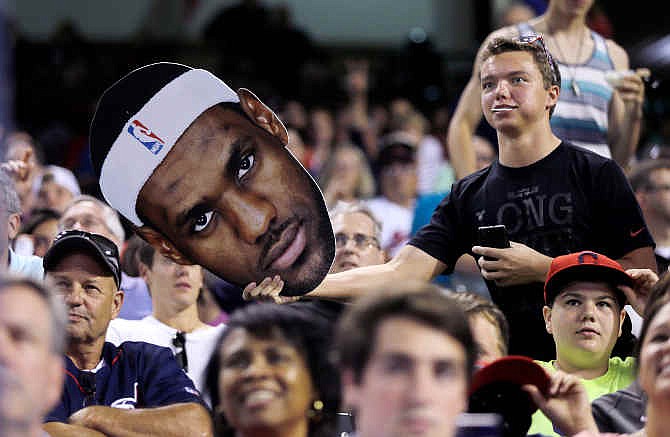 A fan waves a cutout of LeBron James during a baseball game between the Chicago White Sox and Cleveland Indians on Friday, July 11, 2014, in Cleveland. James announced earlier Friday he is returning to play for the Cleveland Cavaliers.