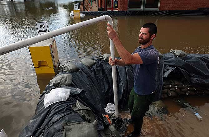 Will Burks, of AmeriCorps St. Louis, gets a sump pump ready to clear floodwater from behind a sandbagged wall in downtown Clarksville, Mo. on Tuesday, July 8, 2014.