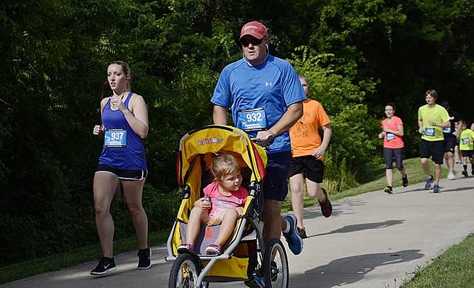 Chad Burks, 38, runs with his three-year-old daughter Charley during the Jefferson City Fire Department's Hotter-N-Hell 5K. Although Burks has run several 5K races and a few half marathons, he had never run while pushing a stroller. "We've got a lot of friends out here that are part of the fire department so it's a good deal to support the locals," he said.