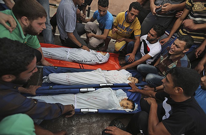 Palestinian mourners gather around the bodies of Jihad Esam Shahebar, 10, Fullah Tariq Shahebar, 8, and Wasim Esam Shahebar, 9, during their funeral in Gaza City, Thursday. The children were killed by an Israeli missile strike at their house feeding pigeons on their roof in the Sabra neighborhood of Gaza City, the family said.