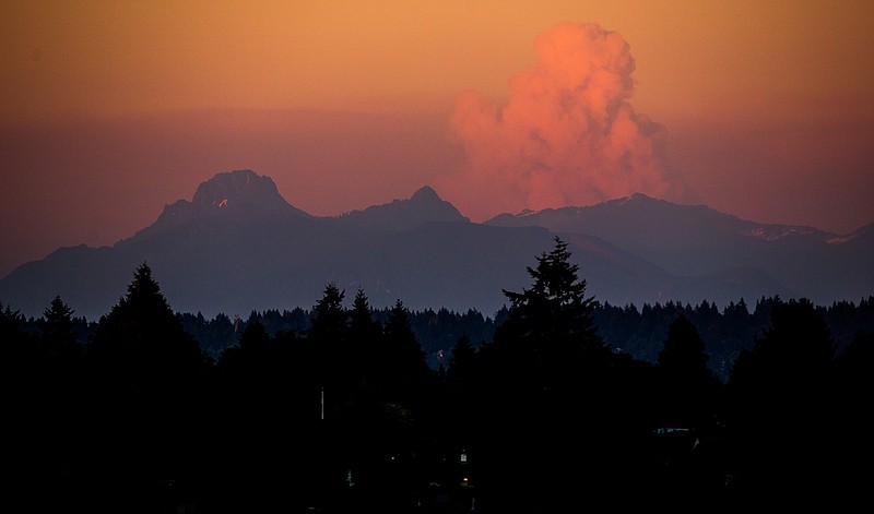 A large cloud rises over wildfires in Eastern Washington as seen from University District at sunset on Wednesday, in Seattle. Worsening wildfire activity has prompted the governor's offices in both Washington and Oregon to declare a state of emergency, a move that enables state officials to call up the National Guard.