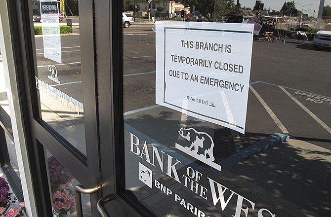 A closed sign is posted on a Stockton, California bank after a robbery. Three bank robbers took three women hostage as they made a getaway and waged a high-speed gunbattle with police that left three people dead and cars and homes riddled with bullets, authorities said. 