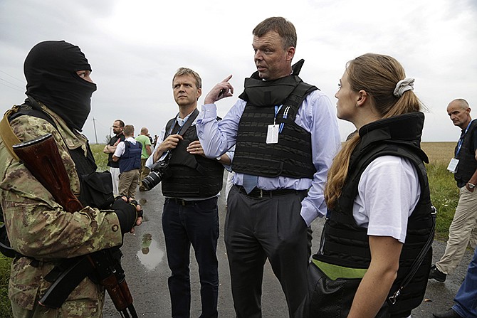 Representatives from the Organization for Security and Cooperation speak to a pro-Russia fighter at the crash site of a Malaysia Airlines jet near the village of Hrabove, Friday. 