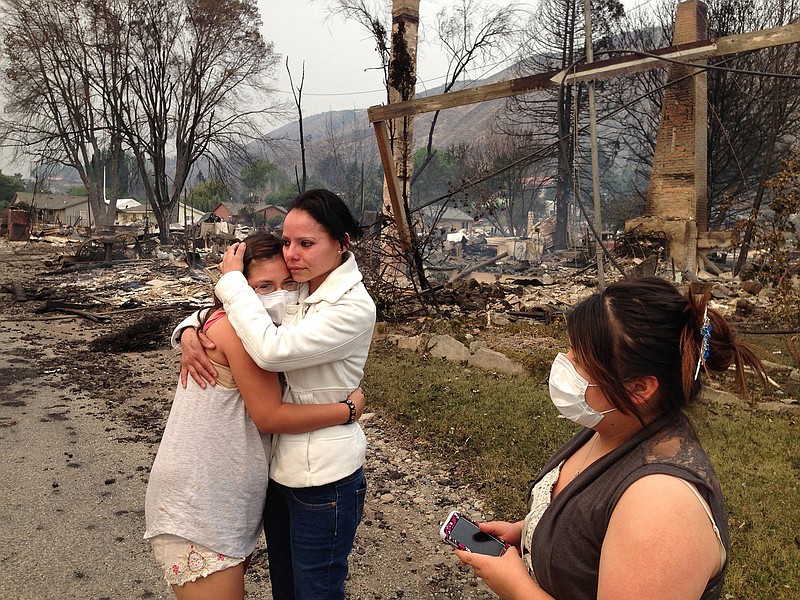 Emma Franco, center, is consoled after she lost her mobile home in the town of Pateros, Washington, on Friday. Authorities say the wildfire has already burned about 100 homes and prompted the evacuation of Pateros, home to about 650 people in Okanogan County.
