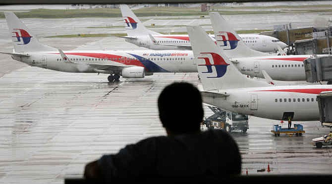 In this Tuesday, May 27, 2014, file photo, a visitor looks out from the viewing gallery as Malaysia Airlines aircrafts sit on the tarmac at the Kuala Lumpur International Airport (KLIA) in Sepang, Malaysia. After the shooting down of Malaysia Airlines Flight 17 on Thursday, July 17, 2014, Malaysia is now grappling with the horrific loss of two of its airplanes, just four months apart.