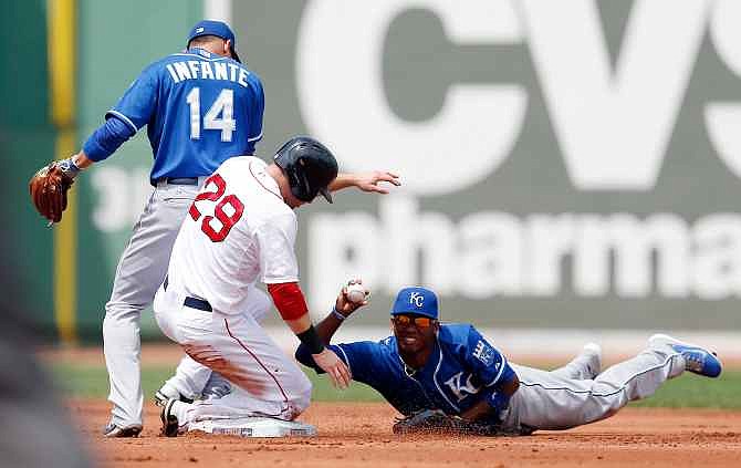 Kansas City Royals' Alcides Escobar, right, holds up the ball next to Omar Infante (14) after getting the forced out on Boston Red Sox's Daniel Nava (29) on a fielders choice during the first inning of a baseball game in Boston, Sunday, July 20, 2014. 