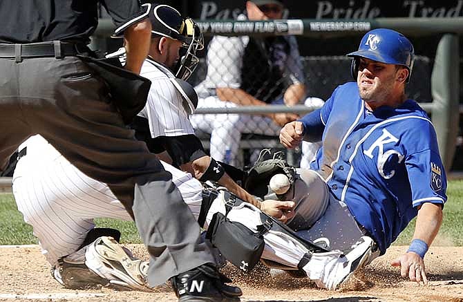 Kansas City Royals' Mike Moustakas knocks the ball out of the glove of Chicago White Sox catcher Tyler Flowers allowing Moustakas to score the winning run during the ninth inning of a baseball game on Wednesday, July 23, 2014, in Chicago. 