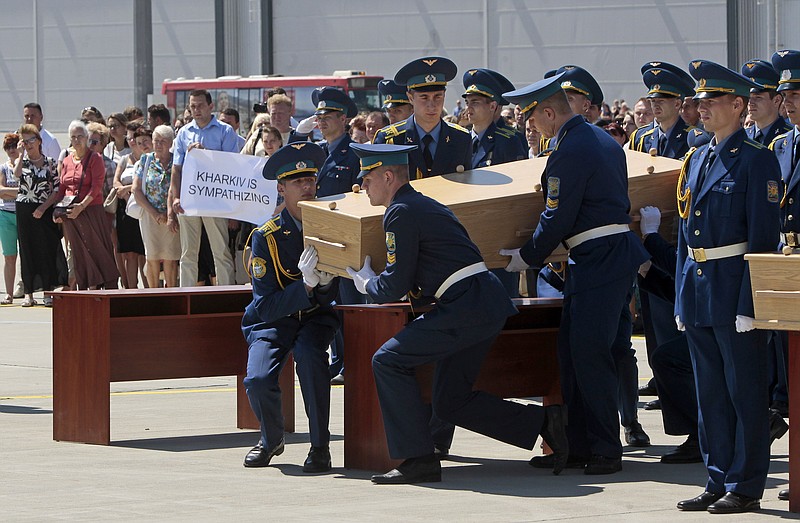 Ukrainian honor guards lift up a coffin, holding the body of one of the Malaysian Airlines plane passengers, to load it onto a Dutch cargo plane in Kharkiv airport, Ukraine, Wednesday,. The Dutch government has declared Wednesday a day of national mourning as the country prepares for the arrival of the first bodies of victims of the downed Malaysia Airlines Flight 17.