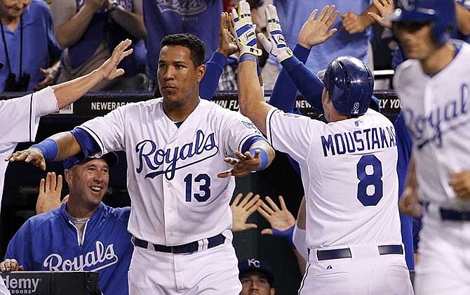 Kansas City Royals' Mike Moustakas (8) celebrates with Salvador Perez (13) and other players after hitting an inside-the-park home run in the eighth inning of a baseball game against the Cleveland Indians at Kauffman Stadium in Kansas City, Mo., Thursday, July 24, 2014. 