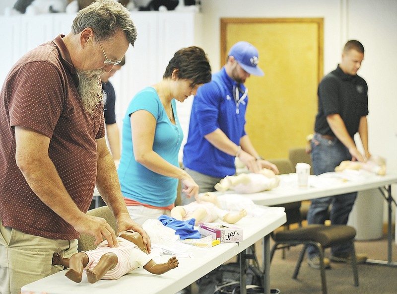 Kirk, near, and fellow students in the Red Cross First Aid/CPR/AED instructor course, perform infant CPR on the mannequin at the Heart of Missouri Chapter office in Jefferson City. Kirk is a volunteer with the Red Cross and furthering his knowledge in lifesaving techniques so he can instruct others.