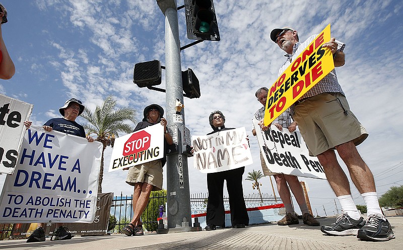 John Zemblidge, right, of Phoenix, leads a group of about a dozen death penalty opponents in prayer as they protest the possible execution of Joseph Rudolph Wood at the state prison in Florence, Arizona on Wednesday. Arizona's highest court temporarily halted the execution of the condemned inmate so it could consider a last-minute appeal.