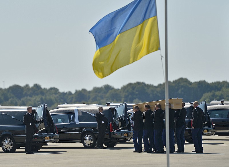 Soldiers load coffins into cars under a Ukrainian flag during a ceremony to mark the return of the first bodies of passengers and crew killed in the downing of Malaysia Airlines Flight 17, from Ukraine at Eindhoven military air base, Wednesday. After being removed from the planes, the bodies were taken in a convoy of hearses to a military barracks in the central city of Hilversum, where forensic experts will begin the painstaking task of identifying the bodies and returning them to their loved ones.