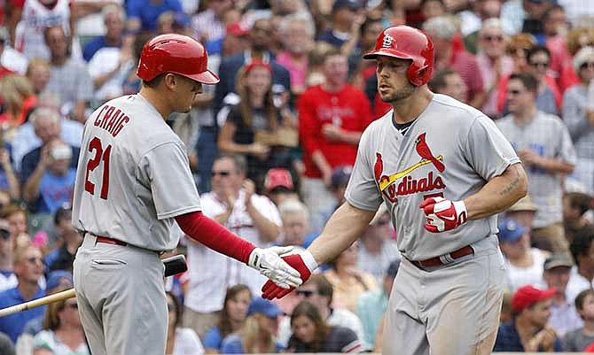 St. Louis Cardinals' Allen Craig (21) greets Matt Holliday outside the dugout after Holliday's home run off Chicago Cubs starting pitcher Travis Wood during the fifth inning of a baseball game Friday, July 25, 2014, in Chicago.