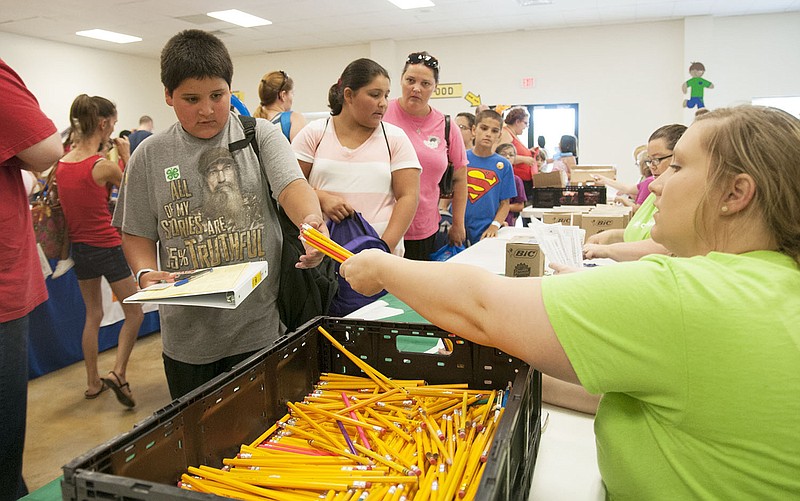 Cruz Ortiz, 10, of Fulton takes a handful of pencils Saturday inside Callaway Christian Church at the Back-to-School Fair organized by SERVE, Inc.