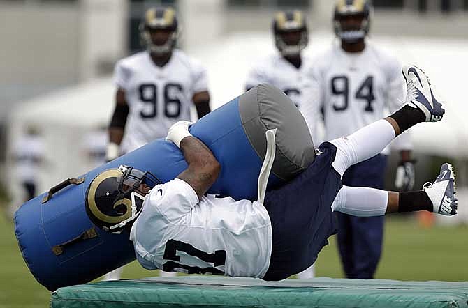 St. Louis Rams defensive end Eugene Sims grabs one pad as he falls onto another during a training camp drill at the NFL football team's practice facility Saturday, July 26, 2014, in St. Louis. 