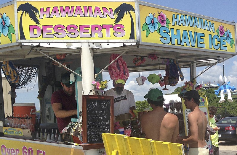 George Manko, second from left, and his son, George A. Manko, left, wait on customers at his concessions trailer in Westerly, R.I. Manko has been cited for defying the town's new ban on street vendors, which he said is prompted by town councilors who don't think street vendors fit the town's image. Town officials said the ban was prompted by safety concerns. A court will now decide.