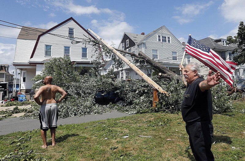 Homeowner Lenny DiBartolomeo, right, waves a flag as he and his tenant Wayne Devaughn, left, observe damage to their house in Revere, Mass., Monday, July 28, 2014 after a tornado touched down. Both men said they were grateful that they knew of no injuries. 