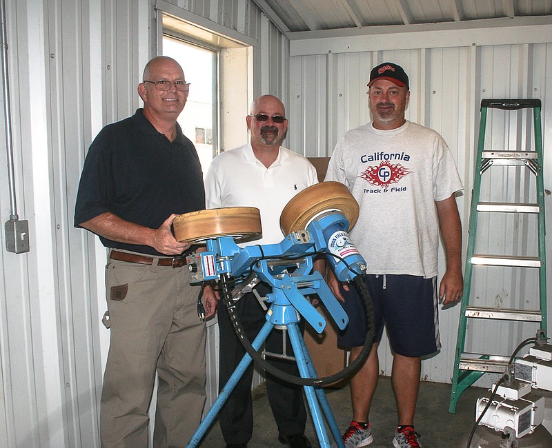 Displaying the JUGS Football Machine donated to the California High School Football Program by Phillips Funeral Home, California, Thursday at the CHS weight room, from left, are Phillips Funeral Home Director Bobby Roll and owner Kevin Simpson, with CHS Activities Director Rick Edwards, who is also an assistant football coach at CHS, as well as the California Middle School Activities Director and CMS Assistant Principal.   