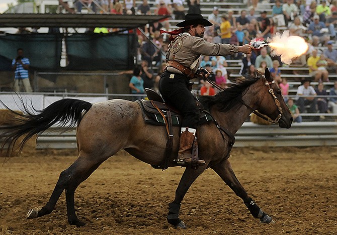 Kelly Kerns fires at a target while racing through the course during Wednesday evening's Show-Me Mounted Shooters competition at the Jefferson City Jaycees Cole County Fair.