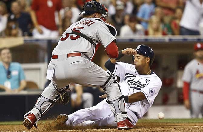 San Diego Padres' Yangervis Solarte is safe at home as St. Louis Cardinals catcher A.J. Pierzynski can't handle the errant throw in the sixth inning of a baseball game Tuesday, July 29, 2014, in San Diego. Solarte scored on hit by Jedd Gyorko.