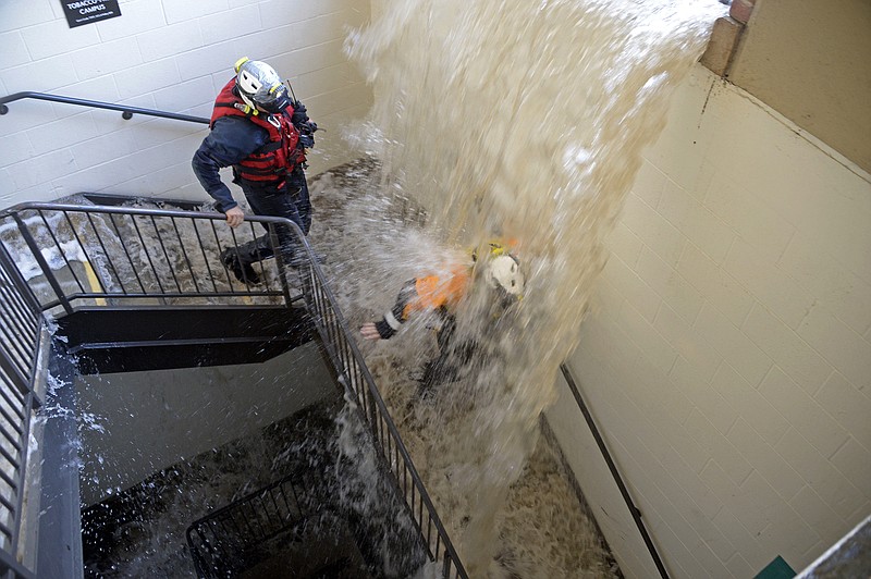 Workers walk down stairs to a parking structure as water cascades down on them on the UCLA campus after flooding from a broken 30-inch water main under nearby Sunset Boulevard inundated a large area of the campus in the Westwood section of Los Angeles, Tuesday. The pipe that broke made a raging river of the street and sent millions of gallons of water across the school's athletic facilities.