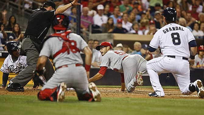 St. Louis Cardinals starting pitcher Joe Kelly looks up to umpire David Rackley who signals San Diego Padres' Alexi Amarista, left, is safe scoring on a wild pitch in the third inning of a baseball game Wednesday, July 30, 2014, in San Diego. San Diego Padres' Yasmani Grandal was batting and the Cardinals catcher is Tony Cruz.