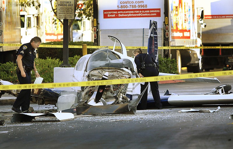 Police examine the wreckage of a small plane in the parking lot of shopping center Wednesday in San Diego. Police said that one woman was killed and one hurt in the crash.