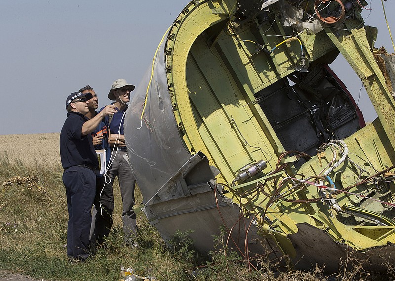Australian and Dutch experts examine a piece of the Malaysia Airlines Flight 17 plane Friday, near the village of Hrabove, Donetsk region, eastern Ukraine. The investigators from the Netherlands and Australia plus officials with the Organization for Security and Cooperation in Europe traveled from the rebel-held city of Donetsk in 15 cars and a bus to the crash site outside the village of Hrabove.